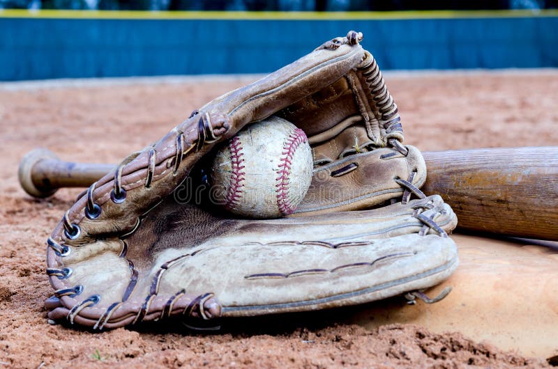 Baseball bat, glove, and ball on base on field. Baseball bat, glove, and ball on base on field.