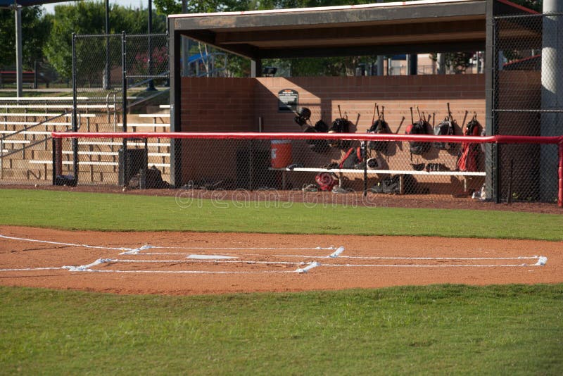 Horizontal photograph of home plate on a baseball field and dugout with baseball gear