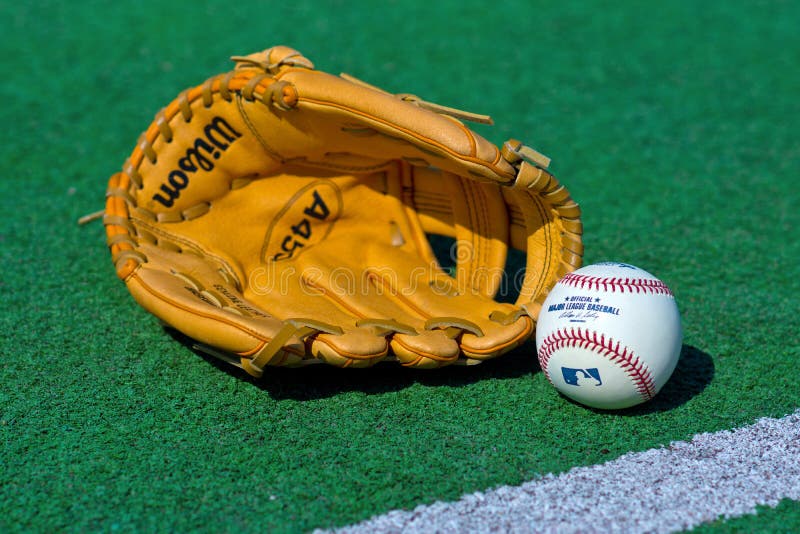 ZAGREB , CROATIA - 13 AUGUST 2015 - official Major League Baseball ball and glove on the green field , product shot. ZAGREB , CROATIA - 13 AUGUST 2015 - official Major League Baseball ball and glove on the green field , product shot