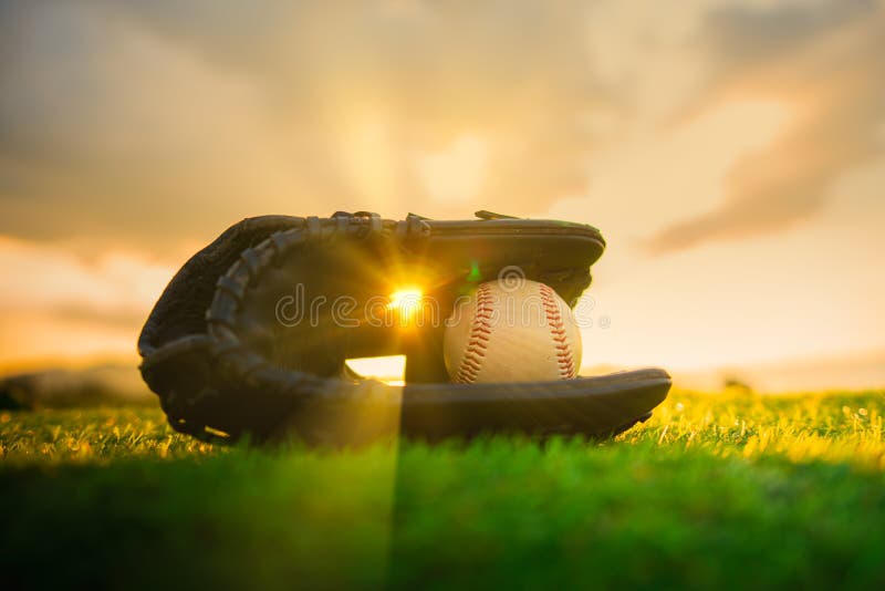 Baseball in glove in the lawn at sunset in the evening day with sun ray
