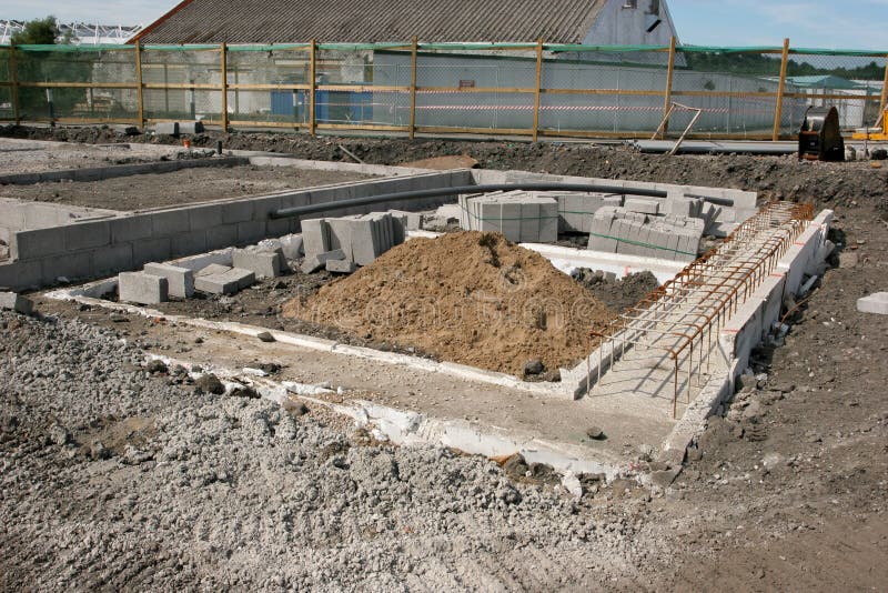 Concrete foundations for a new building on a construction site with sand pile, reinforcing mesh and concrete blocks. Concrete foundations for a new building on a construction site with sand pile, reinforcing mesh and concrete blocks.