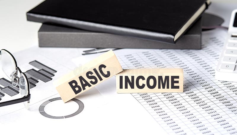 BASIC INCOME - text on a wooden block with chart and notebook stock images