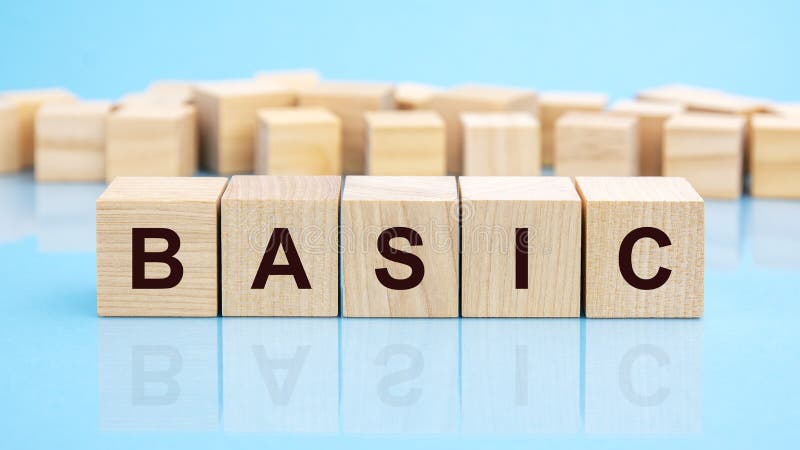 Basic - text of on wooden cubes, reflected from the bright blue surface royalty free stock photos
