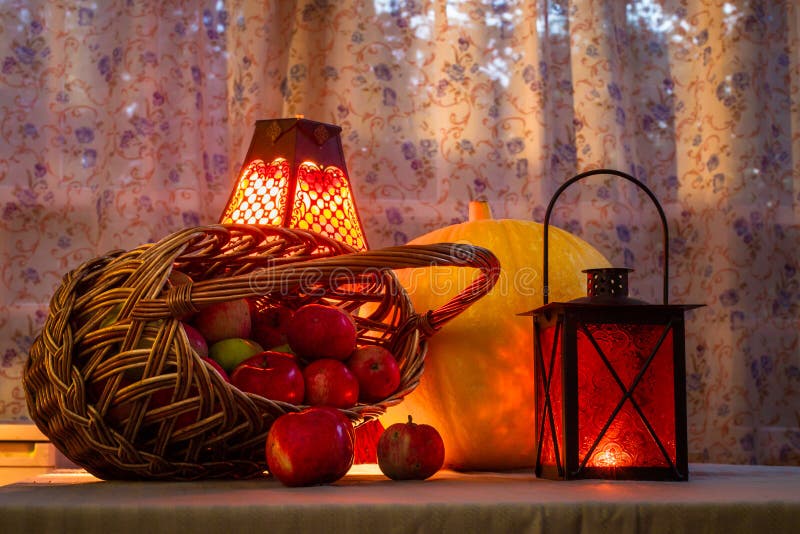 Basket with apples, a large yellow pumpkin lantern old lamp - still life on the day of Thanksgiving and Halloween