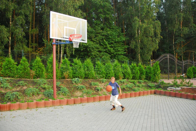 Teen plays basketball on the playground near house. Teen plays basketball on the playground near house