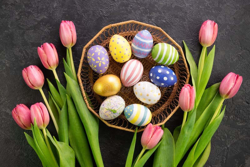 Basket with Easter Eggs and Pink Tulips on a Dark Concrete Background