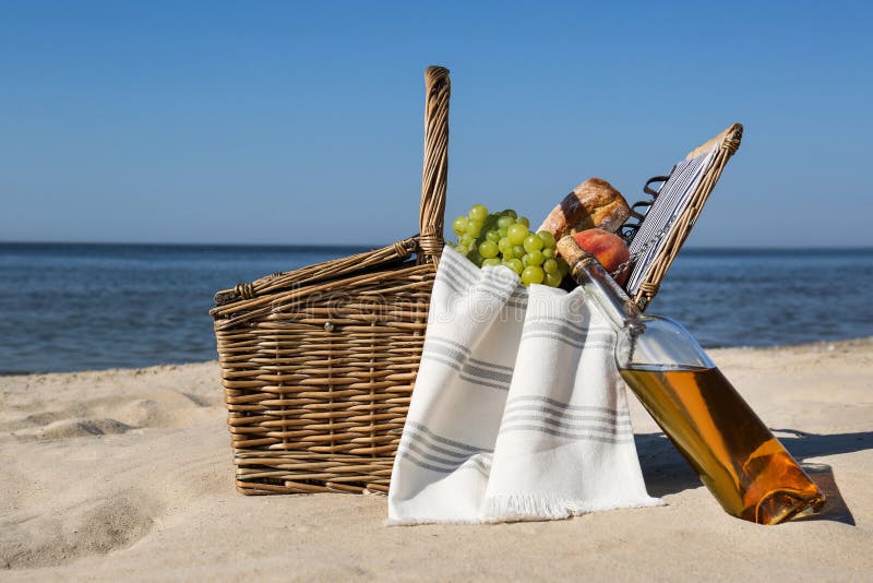 Basket with Food and Bottle of Wine on Beach. Summer Picnic Stock Photo