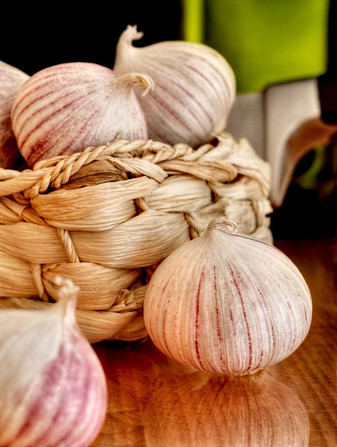 Basket of garlic, oil and knife on a table