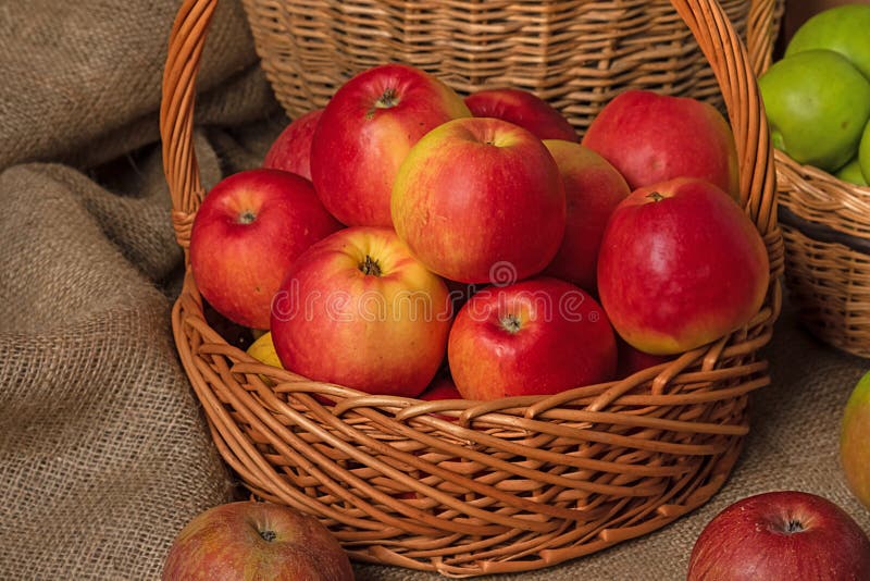 Red apple and green apple in basket with burlap background texture