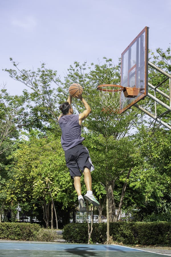 Basketball in Hand Man Jumping Throw a Basketball Hoop on the Wooden