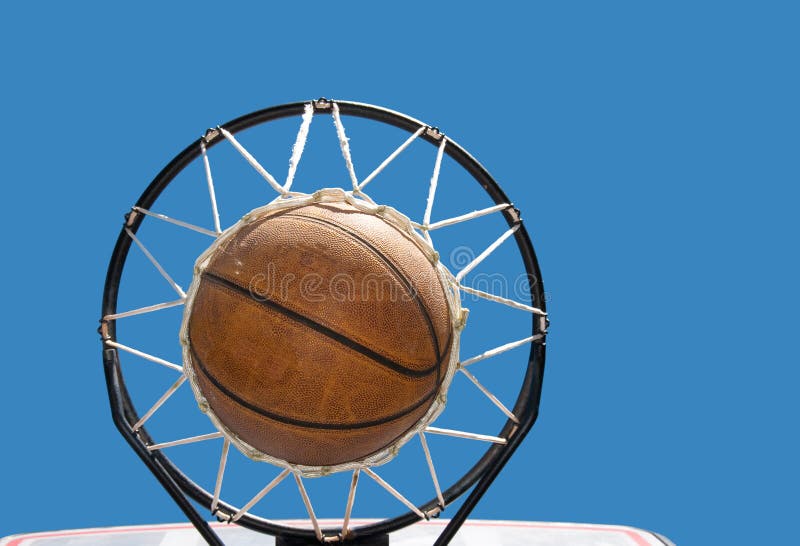 Basketball in the net against clear blue skies