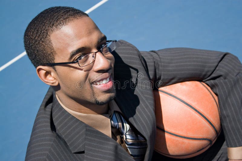 African American man in a business suit posing with a basketball. He could be a coach player recruiter scout or trainer. African American man in a business suit posing with a basketball. He could be a coach player recruiter scout or trainer.