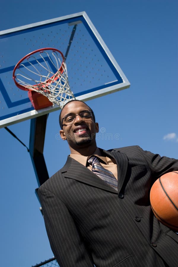 African American man in a business suit posing with a basketball. He could be a coach player recruiter or trainer. African American man in a business suit posing with a basketball. He could be a coach player recruiter or trainer.