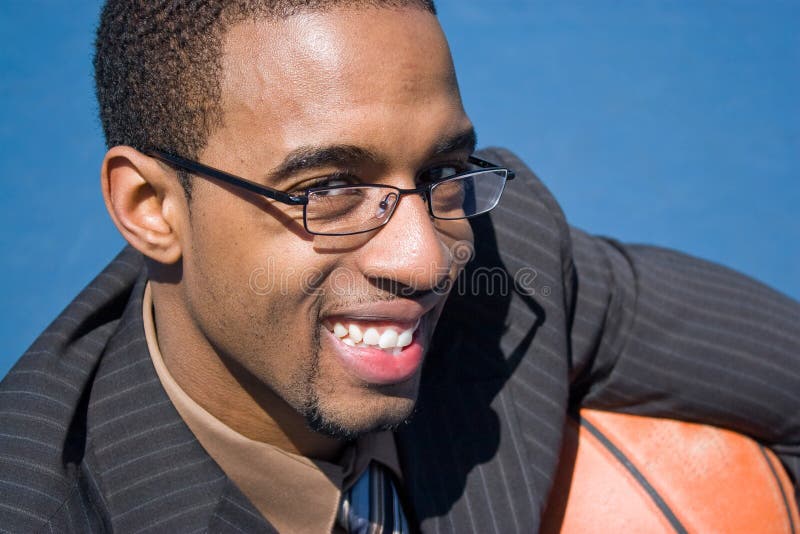 African American man in a business suit posing with a basketball. He could be a coach player recruiter or trainer. African American man in a business suit posing with a basketball. He could be a coach player recruiter or trainer.