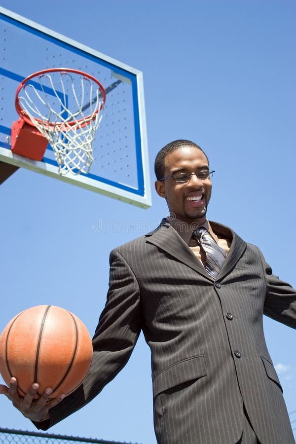 African American man in a business suit posing with a basketball. He could be a coach player recruiter scout or trainer. African American man in a business suit posing with a basketball. He could be a coach player recruiter scout or trainer.