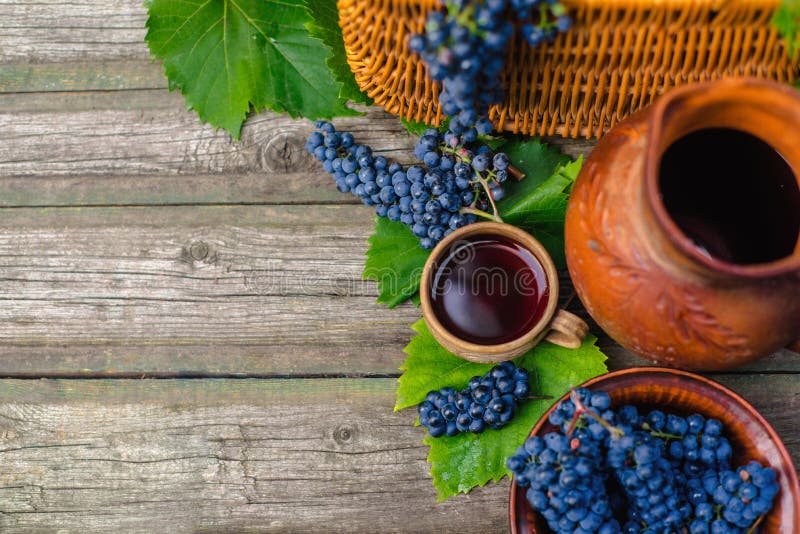 Baskets and bowl with grapes beside Jar and cup with wine stand on on rustic wood. Wine making background. stock photo