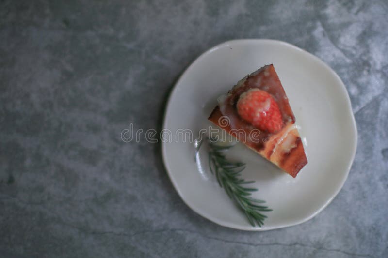 Basque burnt cheesecake with fresh strawberries on white plate cement floor background. Japanese desser