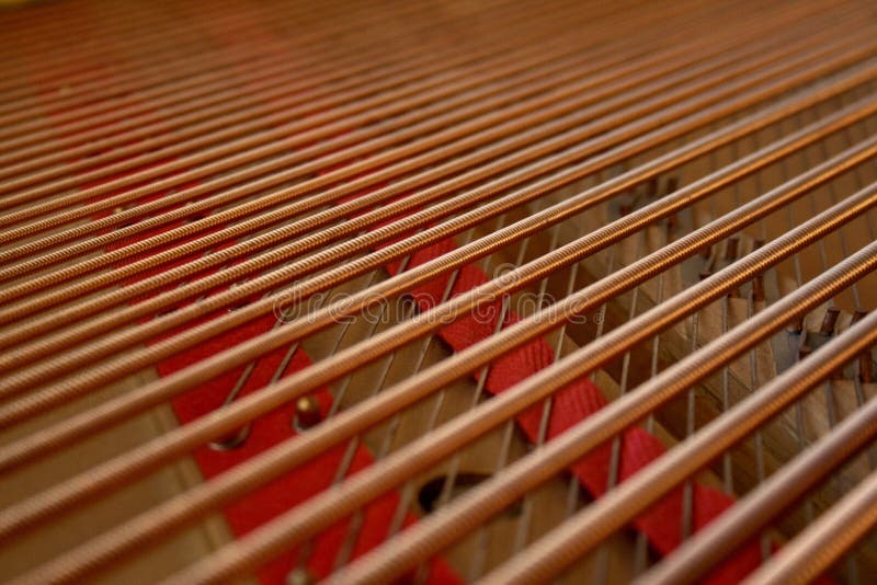 Bass and Treble Strings on Grand Piano. Base and treble strings on an aged grand piano. Copper pins and red felt padding on wooden piano sound board. Rich royalty free stock photography Bass and Treble Strings on Grand Piano. Base and treble strings on an aged grand piano. Copper pins and red felt padding on wooden piano sound board. Rich royalty free stock photography