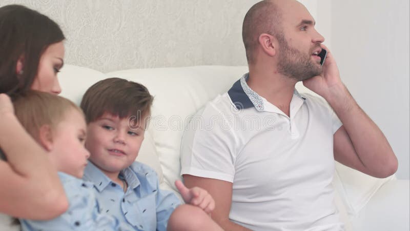 Bastante joven madre jugando con sus niños mientras papá está ocupado por teléfono almacen de video Bastante joven madre jugando con sus niños mientras papá está ocupado por teléfono almacen de video