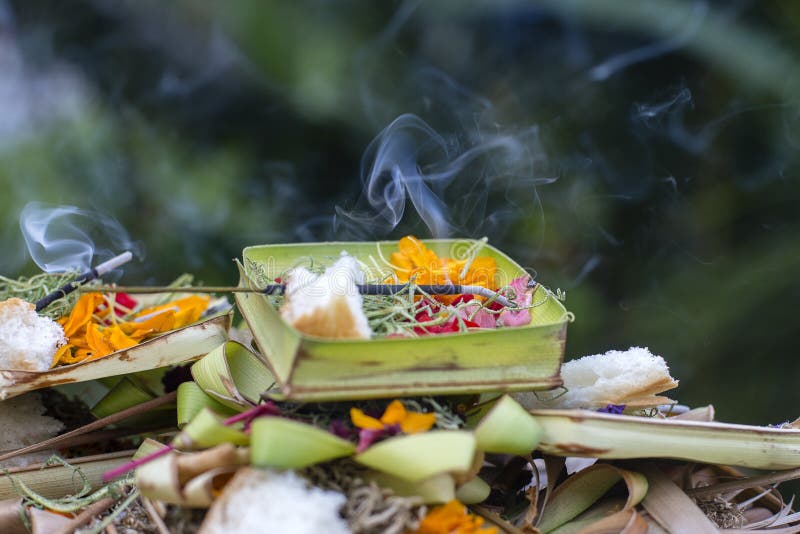 Bastoni brucianti di incenso circondati con le offerti di balinese fuori su un tempio indù in Ubud, Bali, Indonesia fotografie stock libere da diritti Bastoni brucianti di incenso circondati con le offerti di balinese fuori su un tempio indù in Ubud, Bali, Indonesia fotografie stock libere da diritti