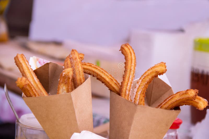 Bastoni deliziosi di churros fritti nel grasso bollente in sacco di carta con zucchero in polvere fotografia stock libera da diritti Bastoni deliziosi di churros fritti nel grasso bollente in sacco di carta con zucchero in polvere fotografia stock libera da diritti