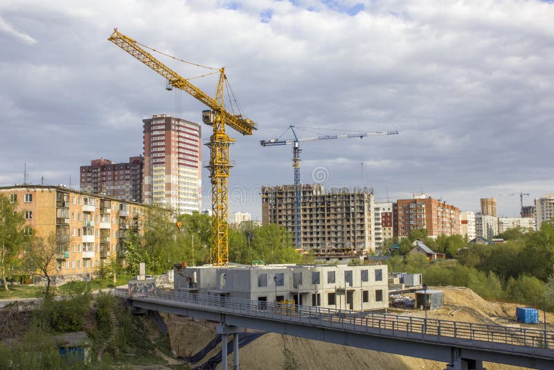 Basztowi żurawie blisko mieścą w budowie blisko mostu przeciw tłu skończeni nowożytni kondygnacja budynki pod a zdjęcia stock Basztowi żurawie blisko mieścą w budowie blisko mostu przeciw tłu skończeni nowożytni kondygnacja budynki pod a zdjęcia stock