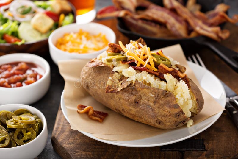 Batata cozida carregada com bacon e queijo fotografia de stock royalty free Batata cozida carregada com bacon e queijo fotografia de stock royalty free