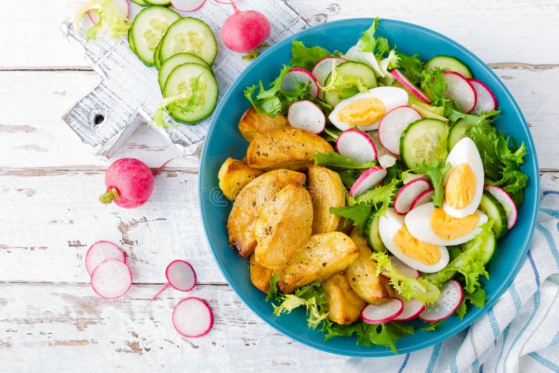 Delicious baked potato, boiled egg and fresh vegetable salad of lettuce, cucumber and radish. Summer menu for detox diet. Top view. Delicious baked potato, boiled egg and fresh vegetable salad of lettuce, cucumber and radish. Summer menu for detox diet. Top view