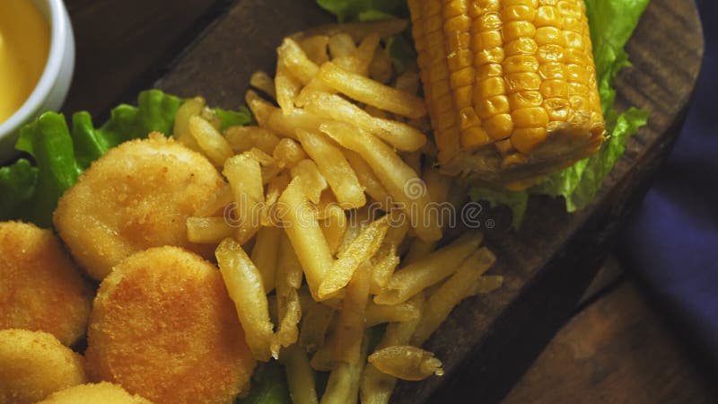 Batatas fritas nuggets e milho em alface