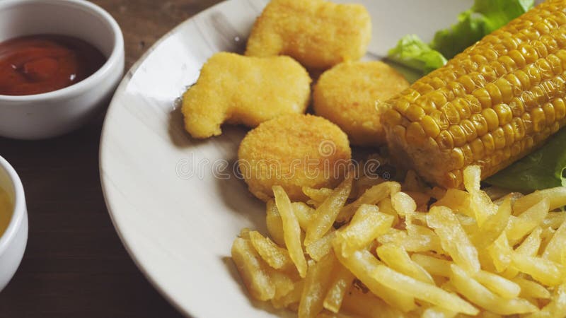 Batatas fritas nuggets e milho em alface