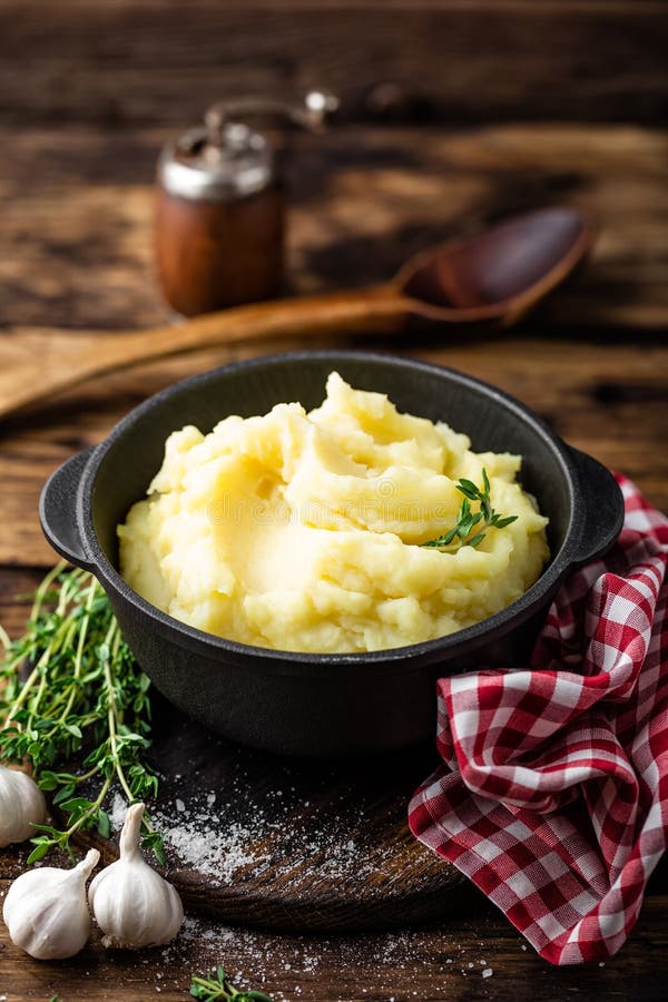 Mashed potatoes, boiled puree in cast iron pot on dark wooden rustic background, top view. Mashed potatoes, boiled puree in cast iron pot on dark wooden rustic background, top view