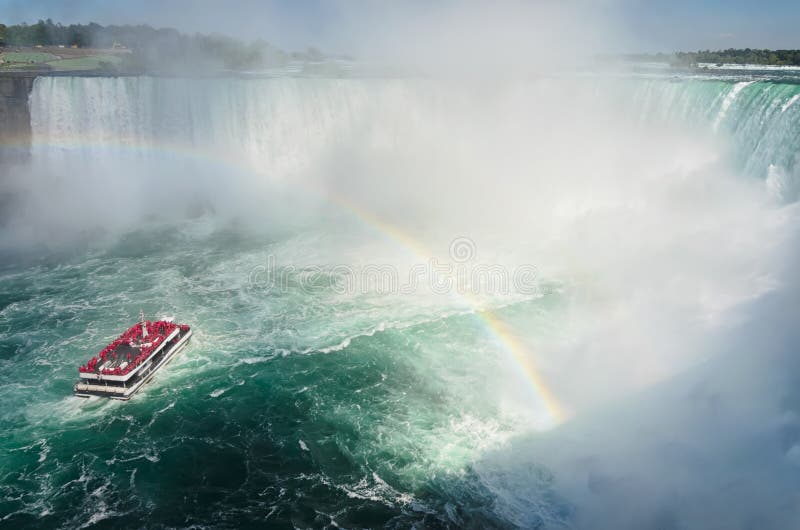Bateau avec des touristes naviguant sous l'arc-en-ciel vers Niagara fal photographie stock libre de droits Bateau avec des touristes naviguant sous l'arc-en-ciel vers Niagara fal photographie stock libre de droits