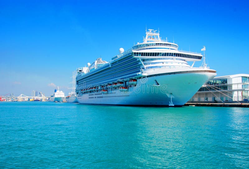 A view of a large cruise ship docked along the waterfront of Barcelona, Spain. A view of a large cruise ship docked along the waterfront of Barcelona, Spain.