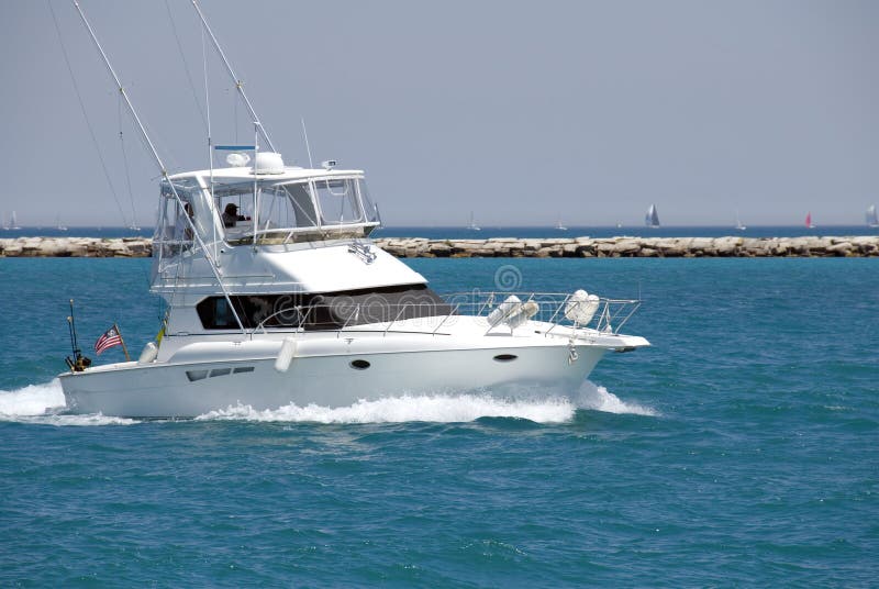 A white sport fishing boat, flying the US Yacht Ensign, heads towards the open sea. A white sport fishing boat, flying the US Yacht Ensign, heads towards the open sea.