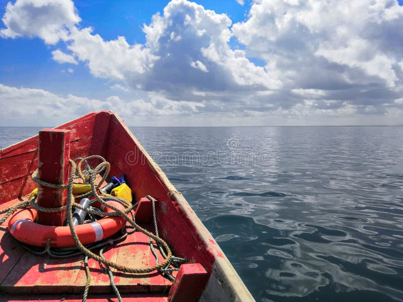 Bateau en bois rouge avec une bou?e de sauvetage en mer un jour ensoleill?, fond de ciel photos libres de droits Bateau en bois rouge avec une bou?e de sauvetage en mer un jour ensoleill?, fond de ciel photos libres de droits