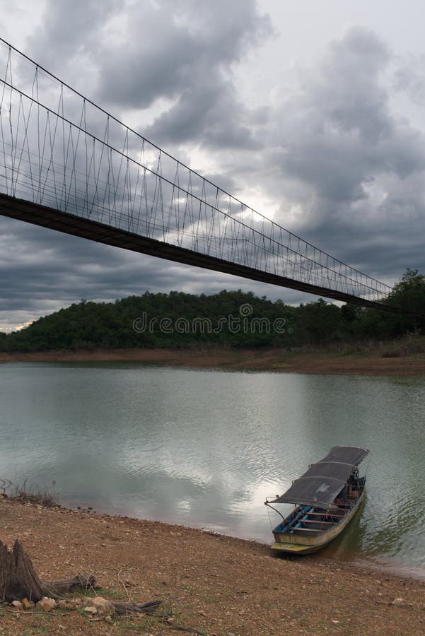 Bateau se reposant sur le rivage d'un lac sous le pont accrochant en parc national, Thaïlande photo stock Bateau se reposant sur le rivage d'un lac sous le pont accrochant en parc national, Thaïlande photo stock
