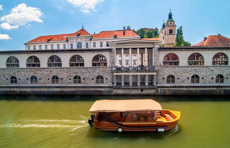 Bateau sur la rivière de Ljubljanica et l'église de Saint-Nicolas dans le backgro images libres de droits Bateau sur la rivière de Ljubljanica et l'église de Saint-Nicolas dans le backgro images libres de droits