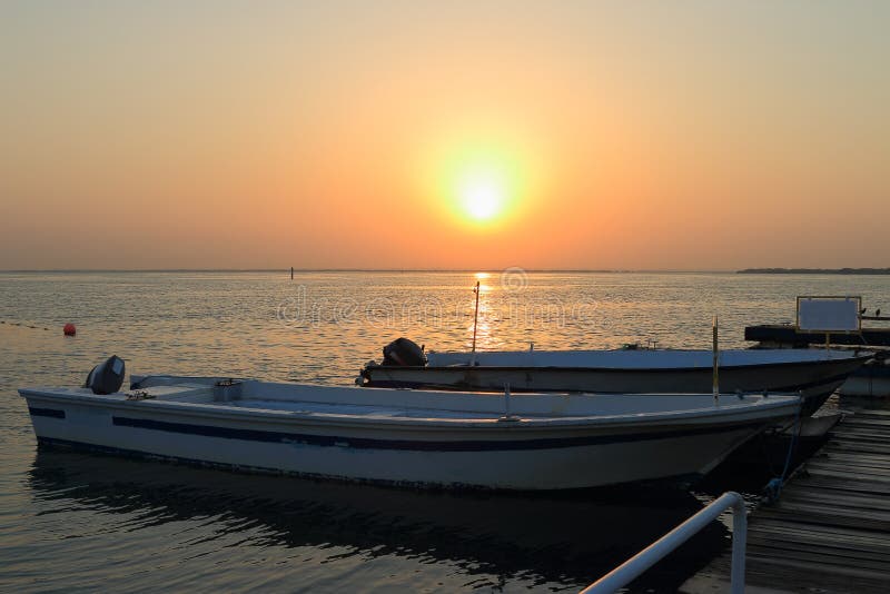 The sunrise over the water area of the harbor of the Persian Gulf in the old town area. Boats moored at a berth cost on calm water. Umm al-Quwain. United Arab Emirates. The sunrise over the water area of the harbor of the Persian Gulf in the old town area. Boats moored at a berth cost on calm water. Umm al-Quwain. United Arab Emirates