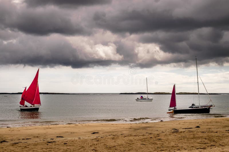 Bateaux à voile avec la voile rouge étant amarrée sur une plage photos libres de droits Bateaux à voile avec la voile rouge étant amarrée sur une plage photos libres de droits