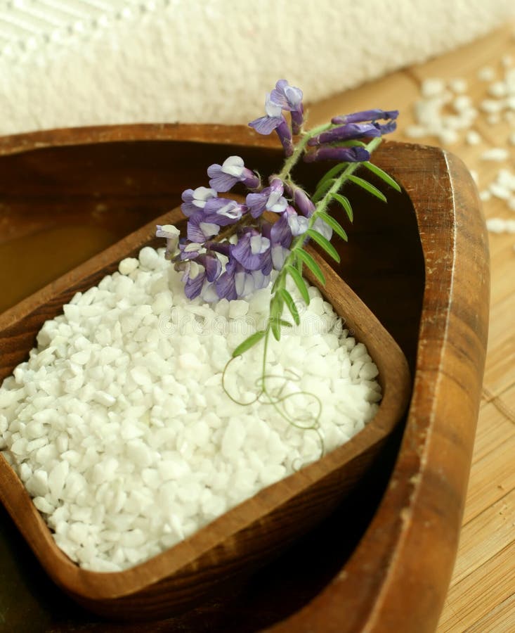 Bath salt in wooden bowl and flowers.