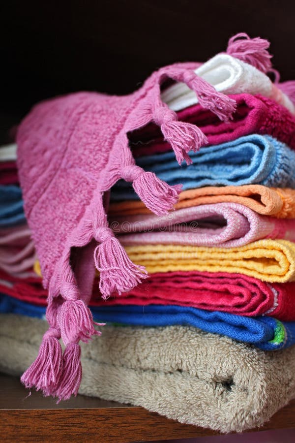 Bath Towel with Fringes Over Folded Towels on Dark Background Stock