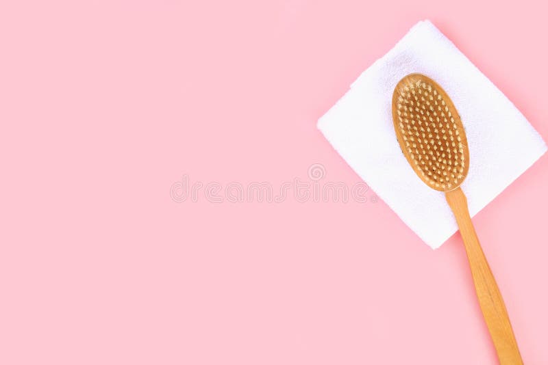 Bathroom accessories on a pastel pink background. Top view, copy space. Brush, loofah, towels, lotion, cream, pence.