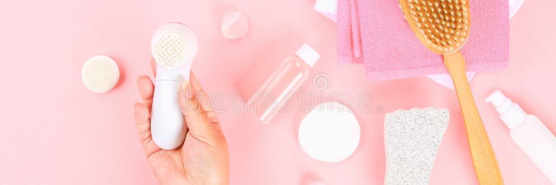 Bathroom accessories on a pastel pink background. Top view, copy space. Brush, loofah, towels, lotion, cream, pence. Face