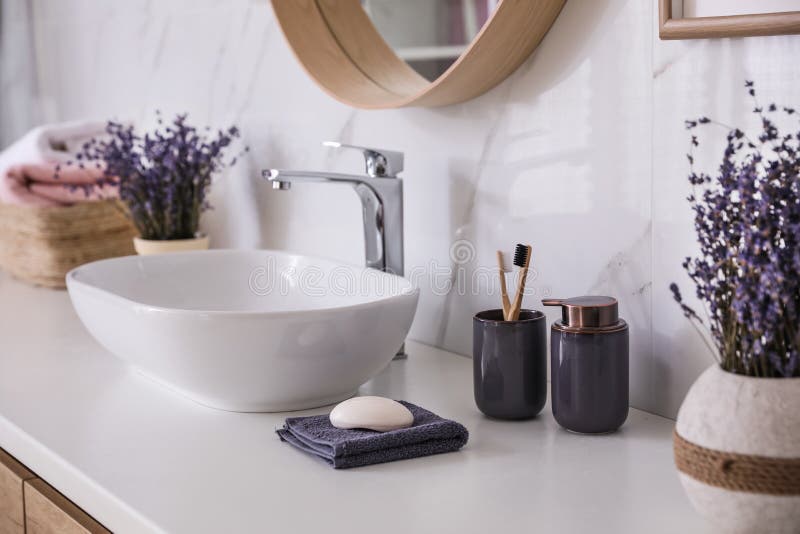 Bathroom counter with vessel sink, accessories and flowers. Interior