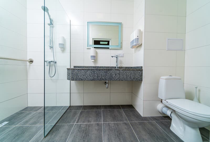 Bathroom in modern hospital. Grey and white colors in interior. Fully equipped commercial toilet in hospital. Closeup..
