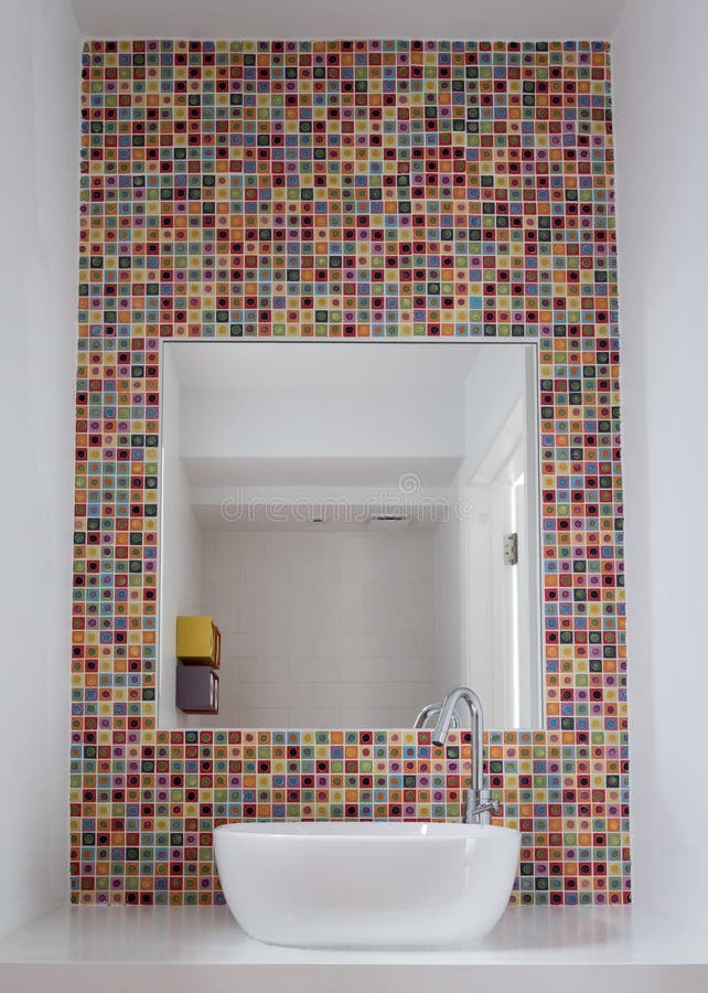 Bathroom wash basin with colorful glass mosaic tiles and mirror inset into the tiles