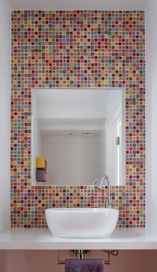 Bathroom wash basin with colorful glass mosaic tiles and mirror inset into the tiles