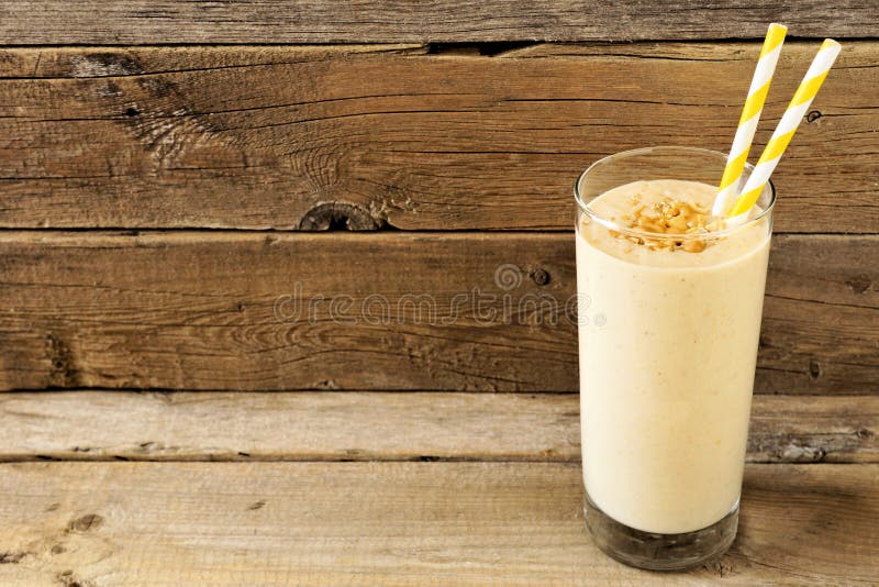 Batido da aveia da banana da manteiga de amendoim com palhas sobre a madeira rústica fotos de stock Batido da aveia da banana da manteiga de amendoim com palhas sobre a madeira rústica fotos de stock