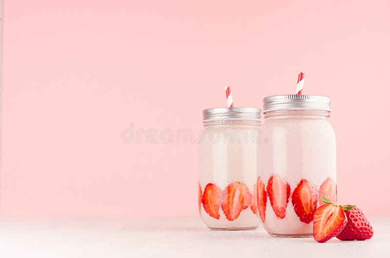 Batido de leche fresco de la fresa del verano en tarros con las frutas brillantes, casquillos de plata, paja rayada roja en fondo imagen de archivo libre de regalías Batido de leche fresco de la fresa del verano en tarros con las frutas brillantes, casquillos de plata, paja rayada roja en fondo imagen de archivo libre de regalías