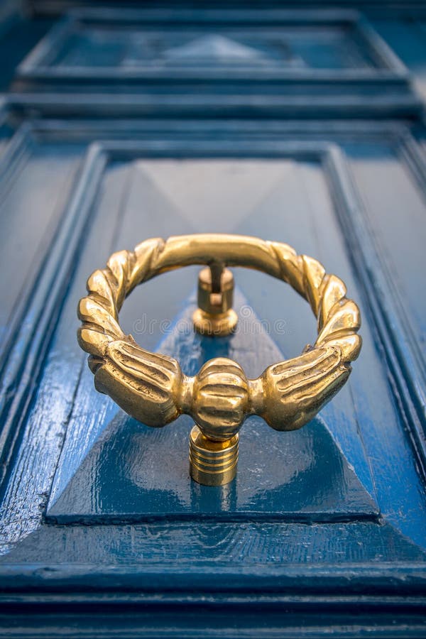 Battitore di porta d'ottone antico sulla porta blu fotografie stock Battitore di porta d'ottone antico sulla porta blu fotografie stock